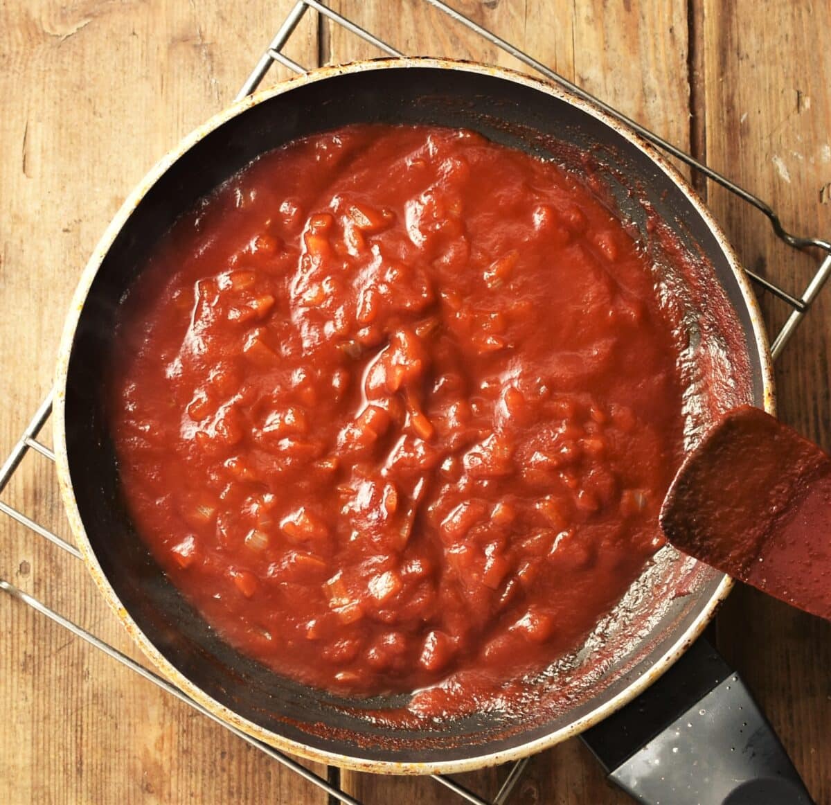 Homemade bbq sauce in pan with red spatula to the right.