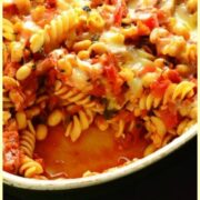 Top down view of bean pasta bake in oval casserole dish on oven tray.