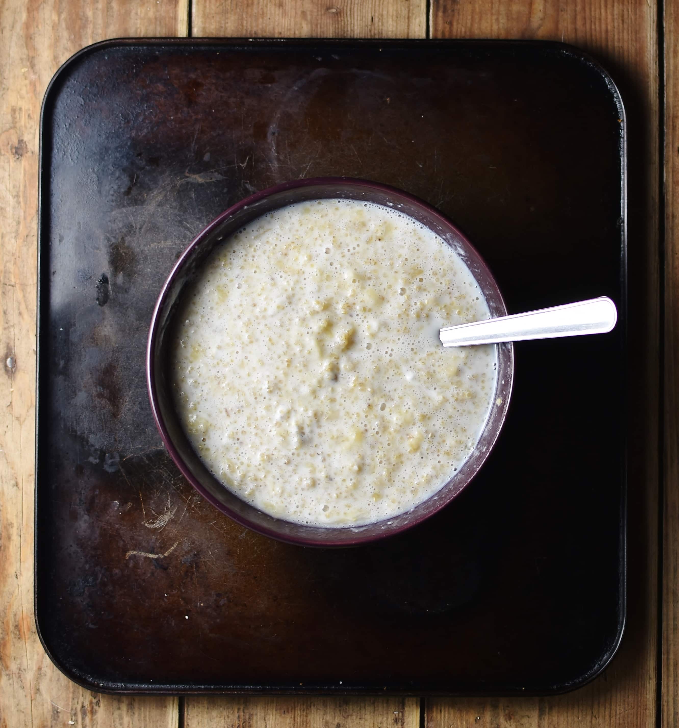 Top down view of overnight quinoa mixture inside purple bowl with spoon.