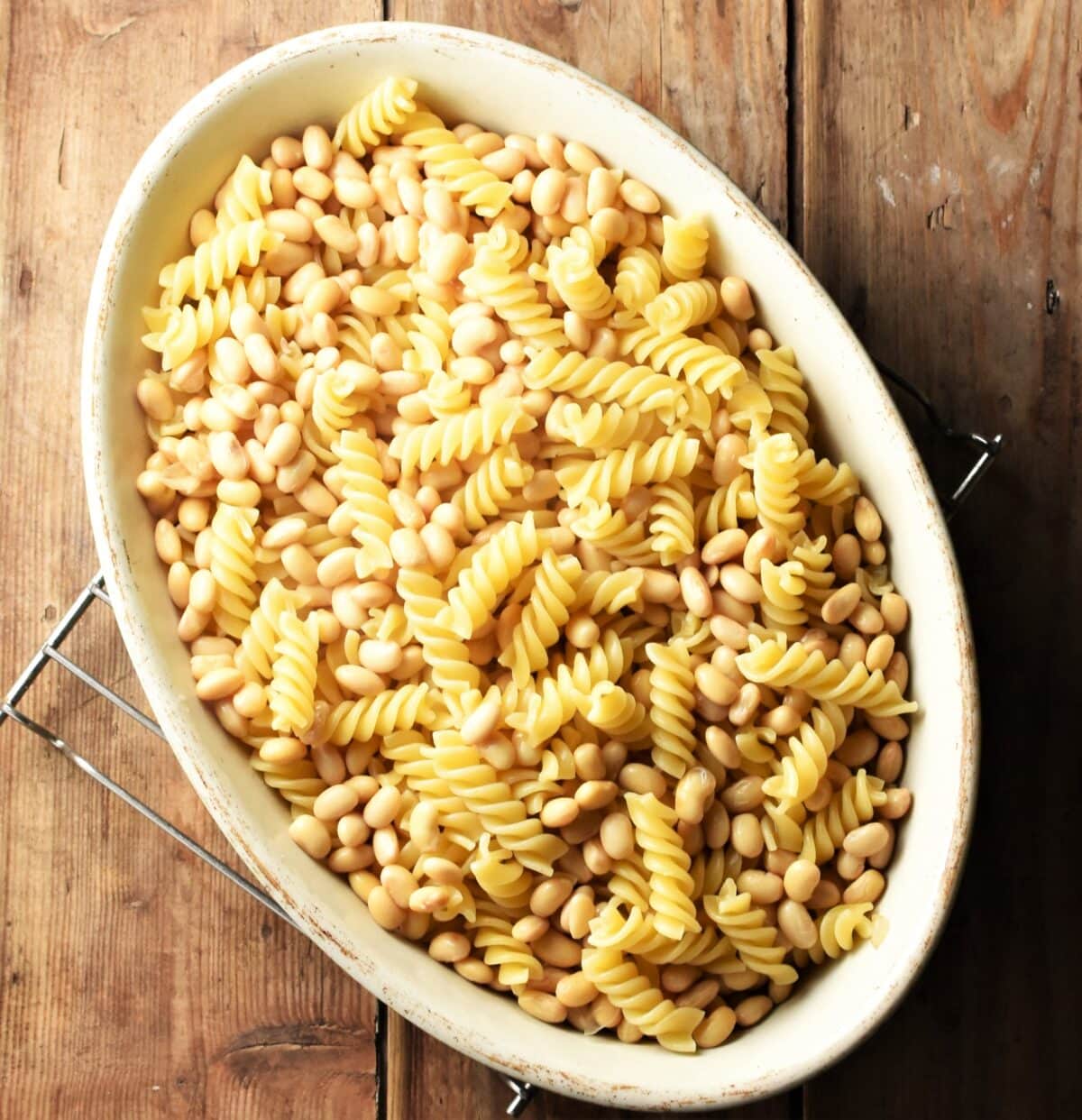 Fusilli pasta and beans in oval white casserole dish.