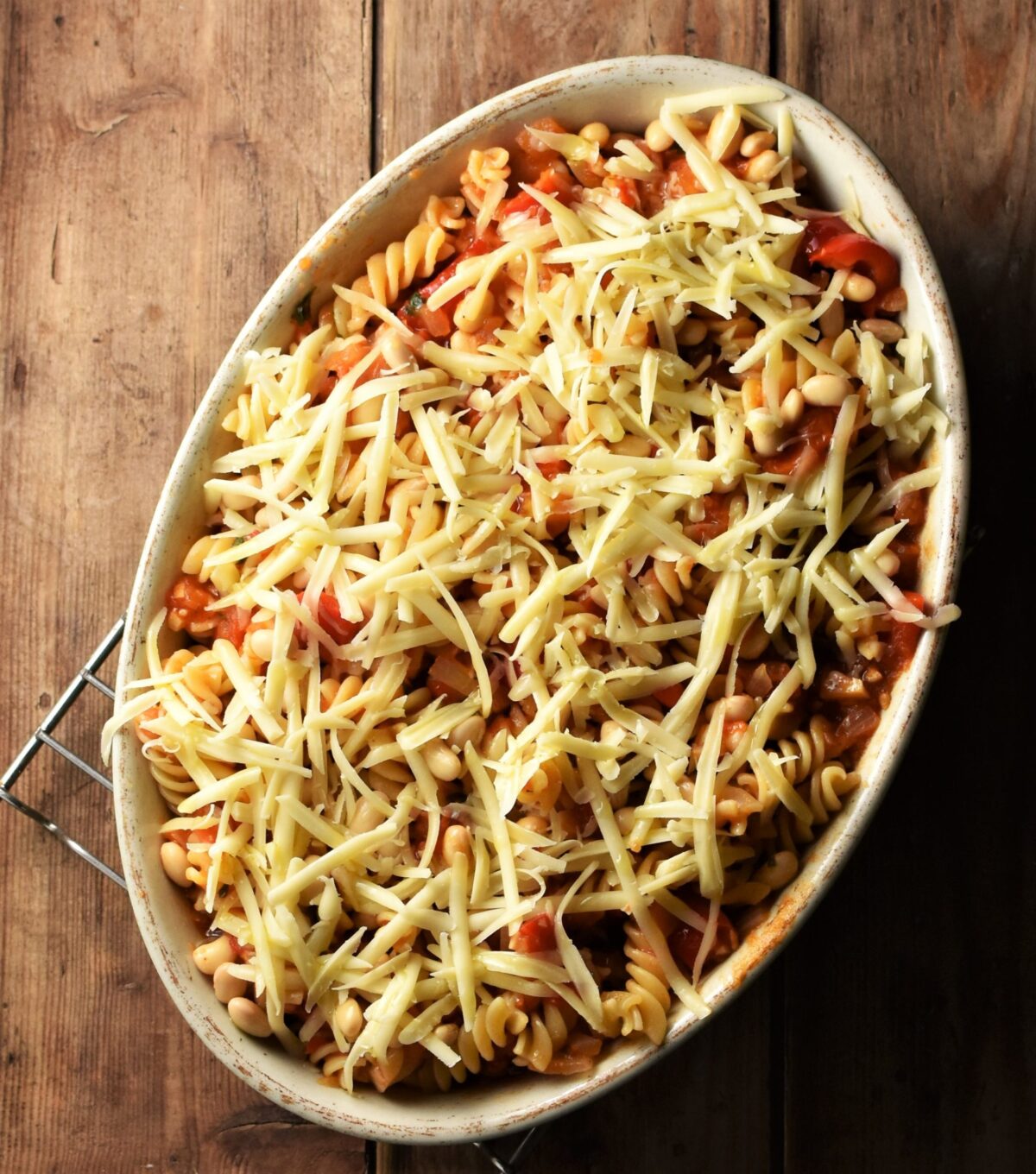 Fusilli pasta with tomato sauce and grated cheese in white oval casserole dish.