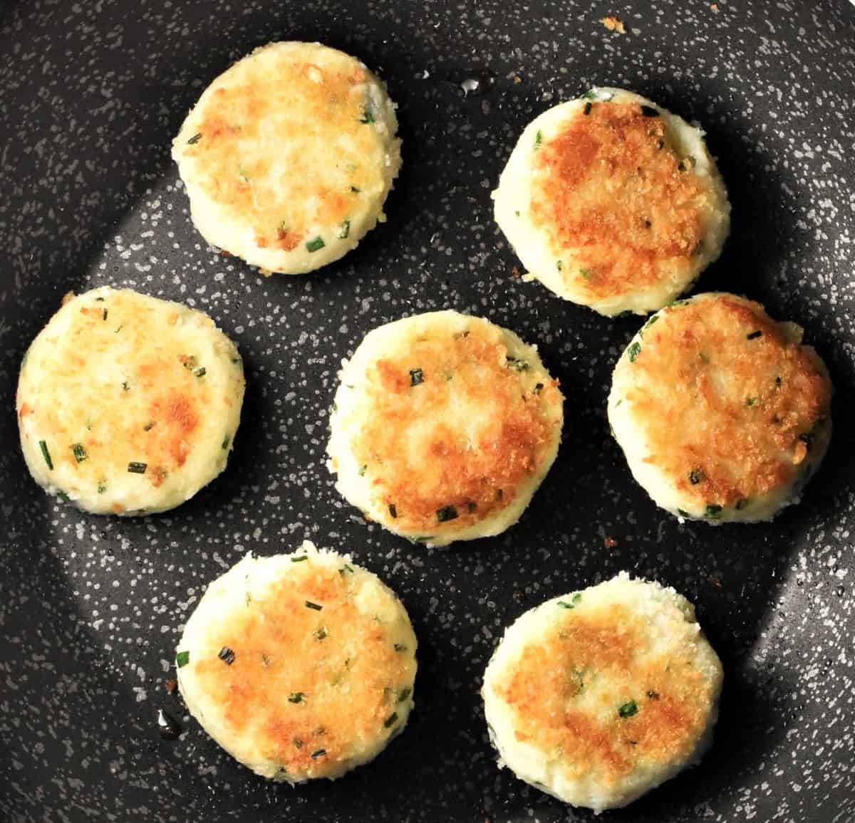 Frying fish and potato cakes in pan.