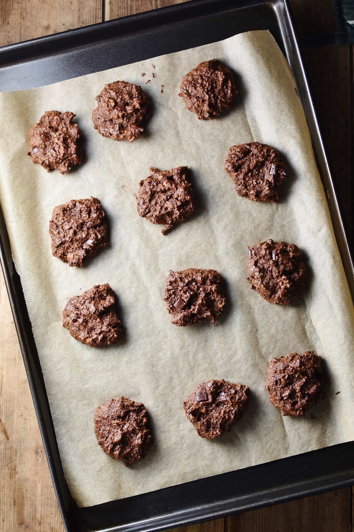 Unbaked chocolate cookies on top of cookie sheet lined with parchment paper.