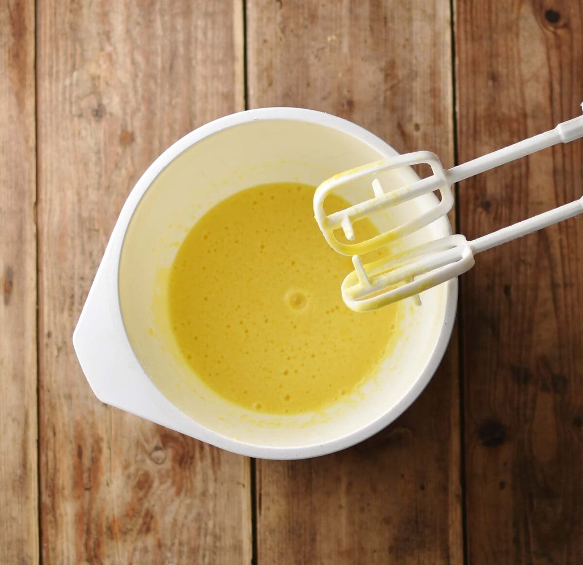 Beaten eggs and oil inside white bowl.