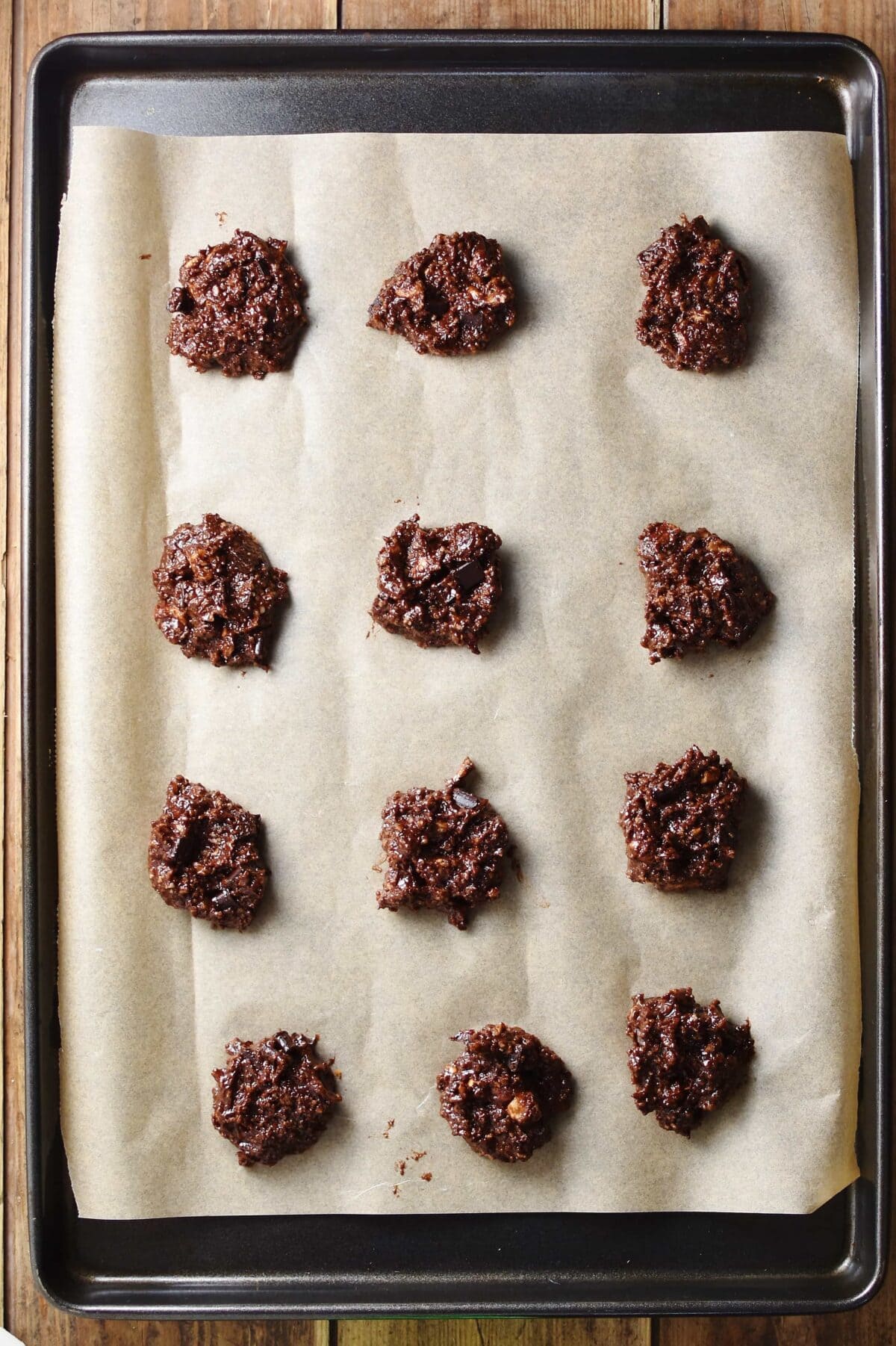 Chocolate cookies on top of cookie sheet lined with paper.
