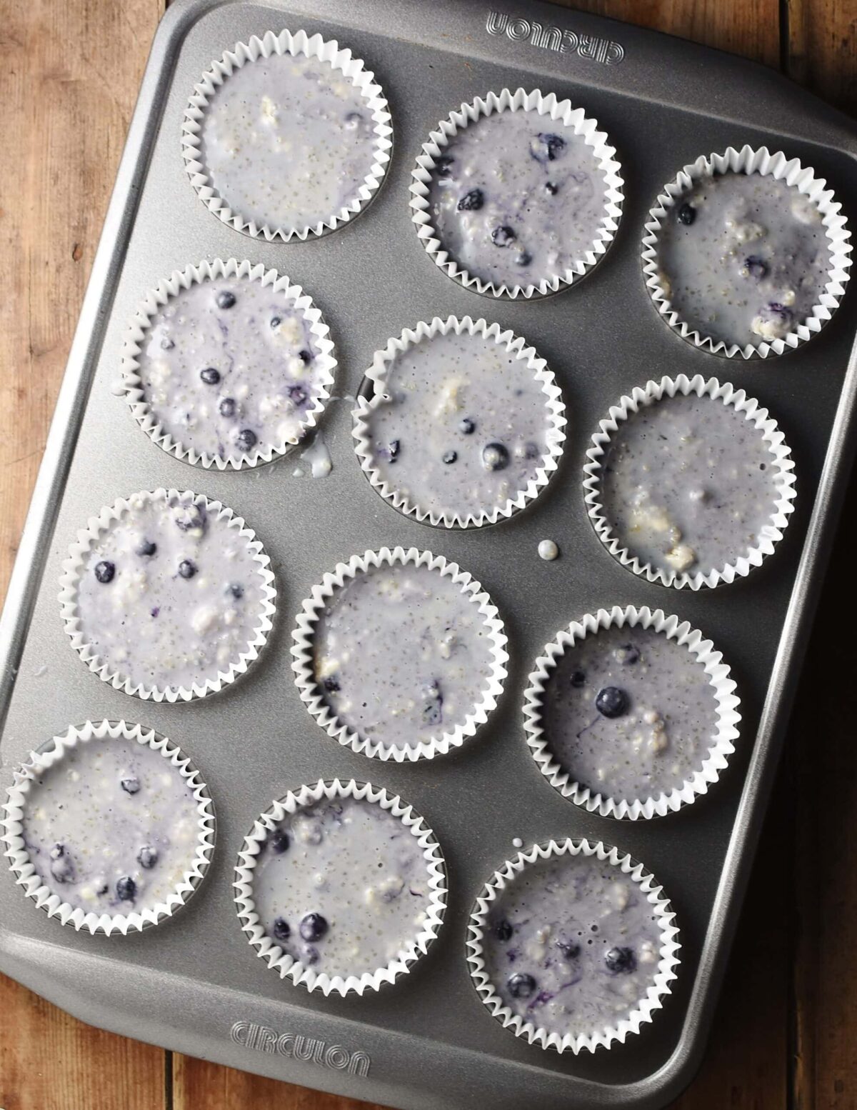 Unbaked muffins in 12 paper cases inside muffin pan.