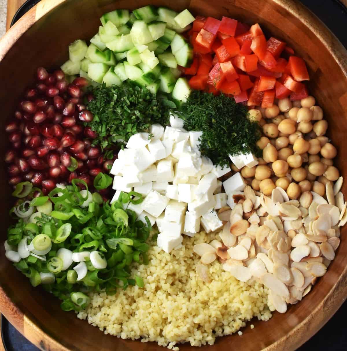 Individually displayed ingredients for bulgur salad in large wooden bowl.