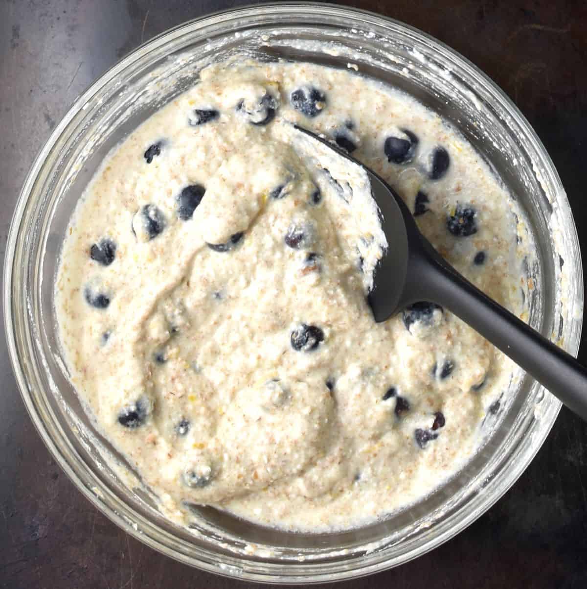Top down view of blueberry ricotta batter in glass bowl with whisk.
