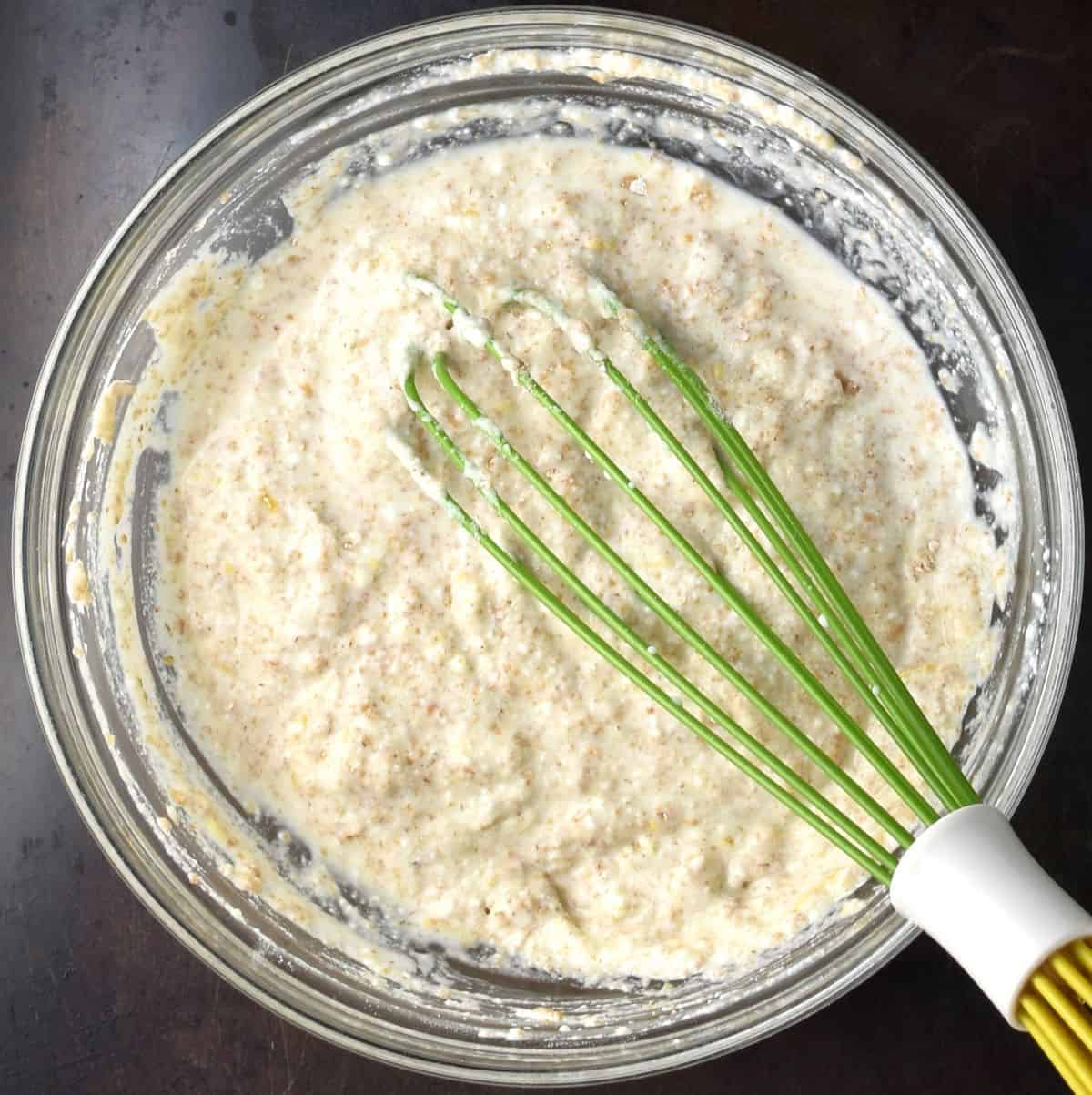Thick whole wheat pancake batter in bowl with whisk.
