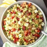 Top down view of bulgur salad with pomegranate seeds, feta and chickpeas in grey bowl.