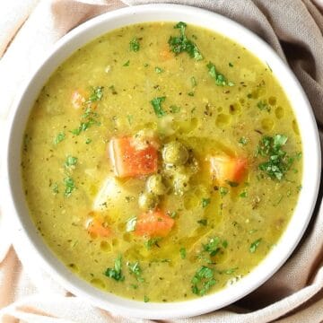 Top down view of canned pea soup with vegetables in white bowl.