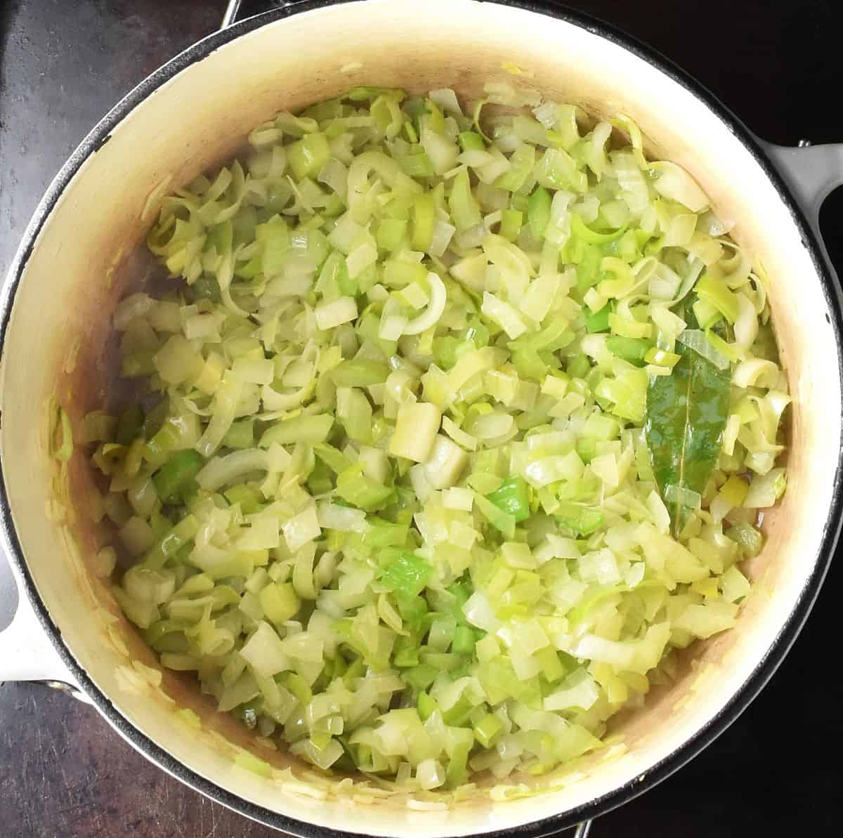 Chopped onion and leek in large white pot.