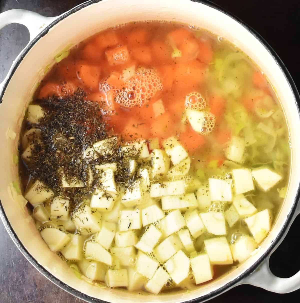 Canned pea soup with cubed carrots and parsnips in white pot.