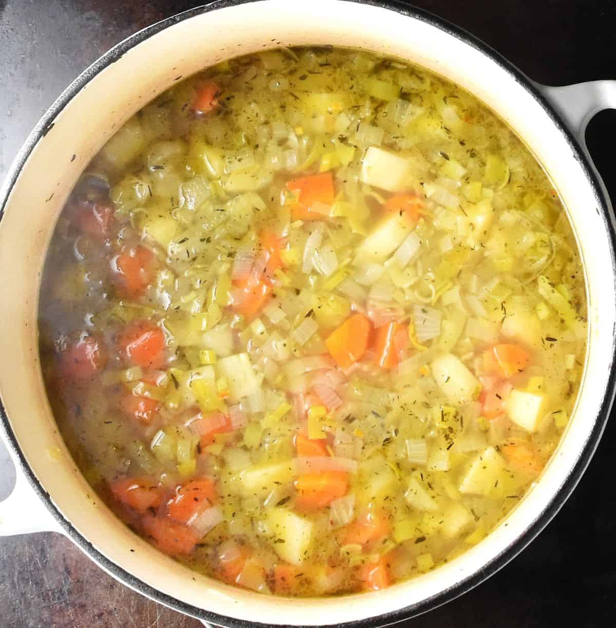 Top down view of chunky canned pea soup in white pot.
