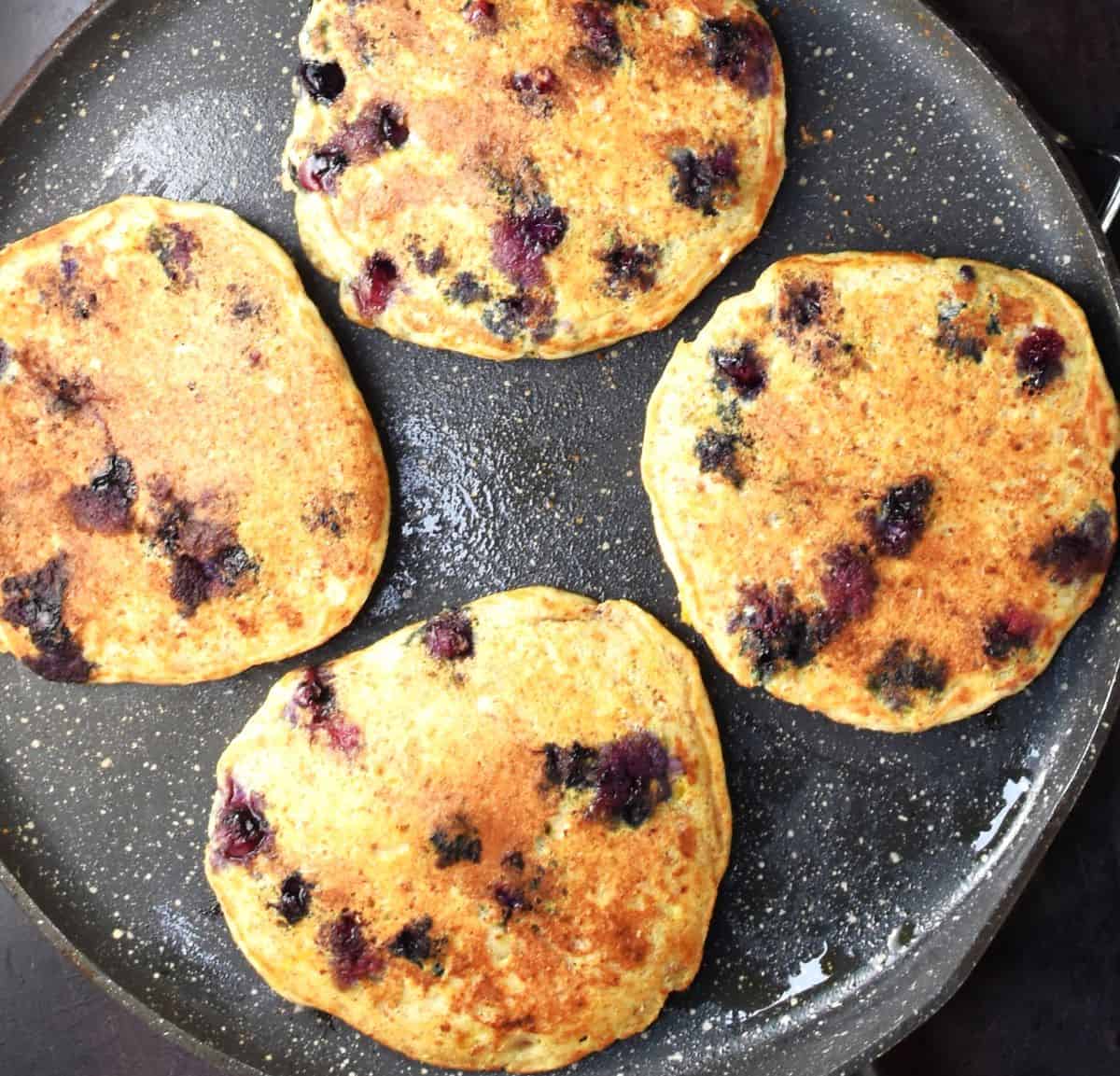 4 ricotta blueberry pancakes in large pan.