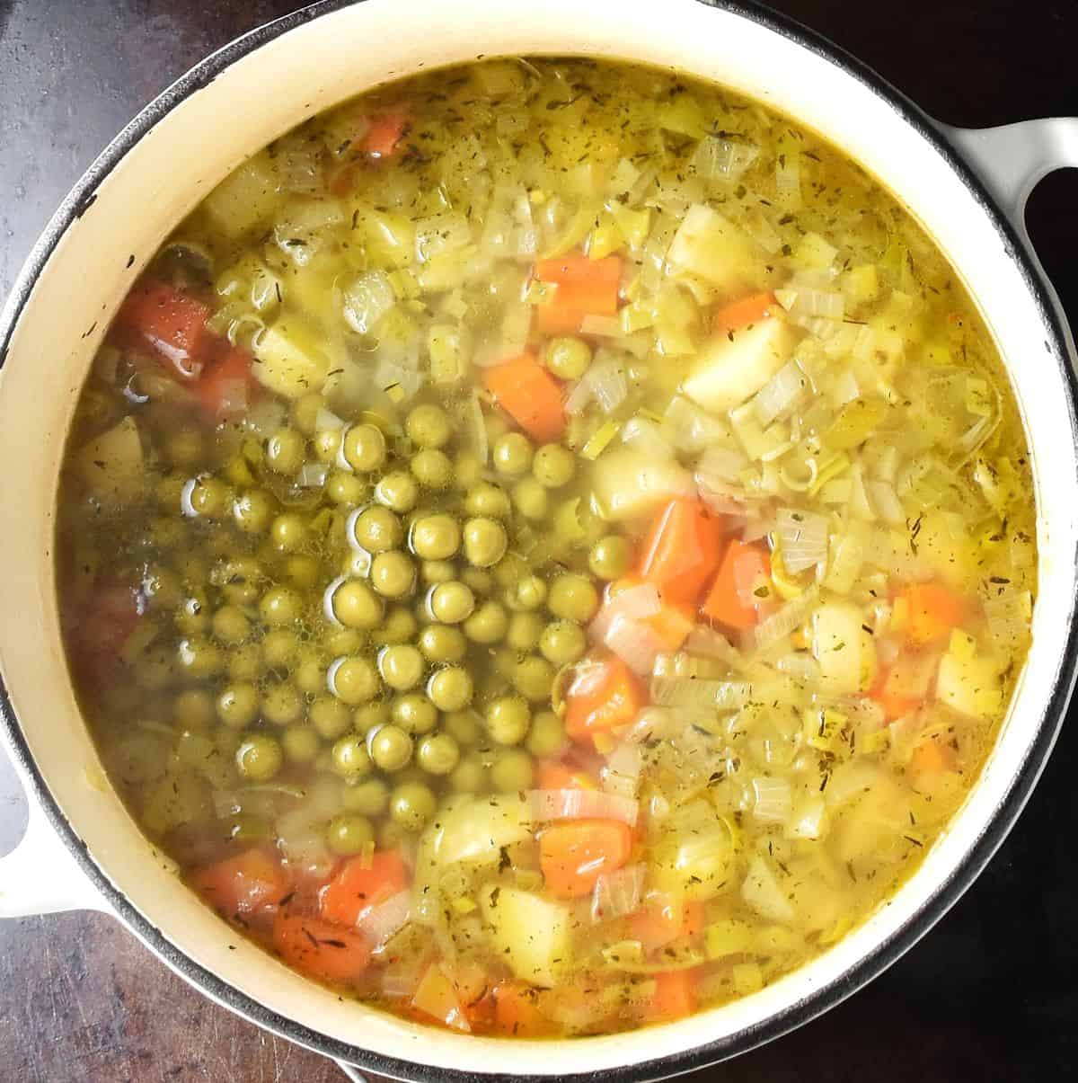 Canned pea soup with cubed vegetables in large pot.