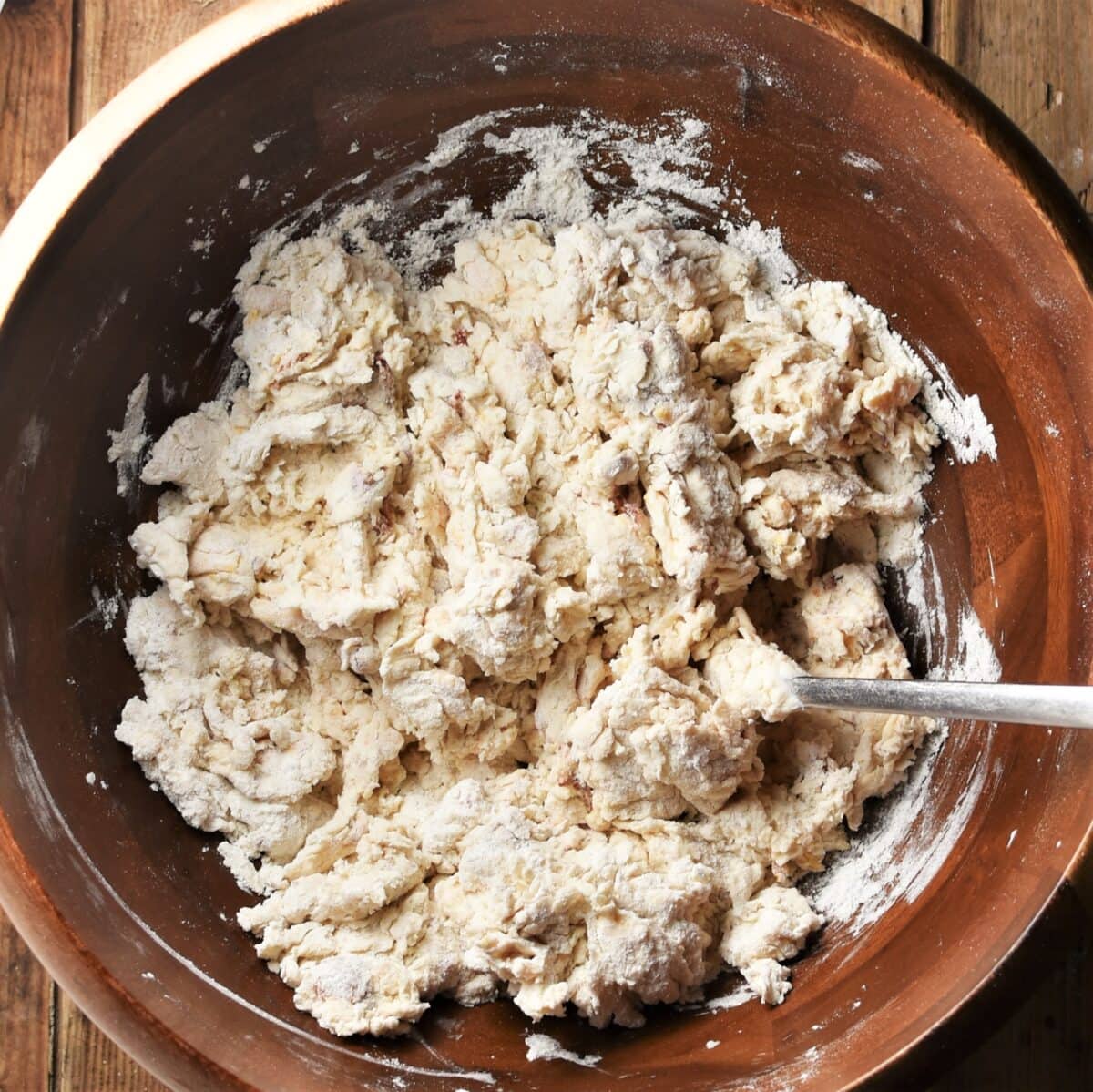 Bread dough mixture in wooden bowl with fork.