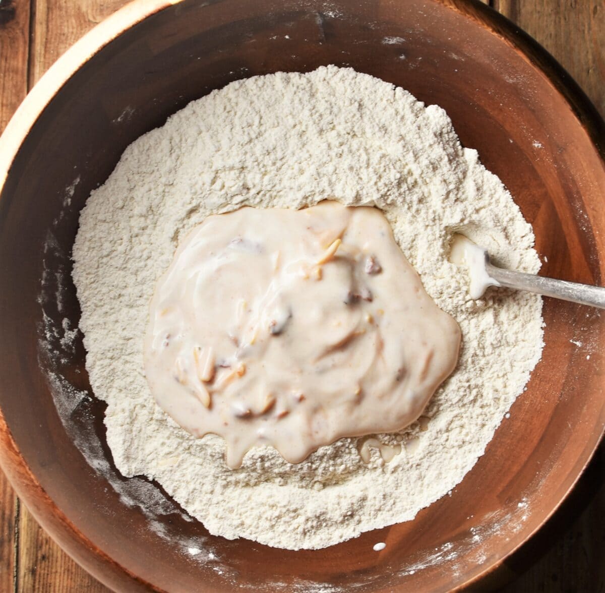 Flour and buttermilk in wooden bowl with fork.