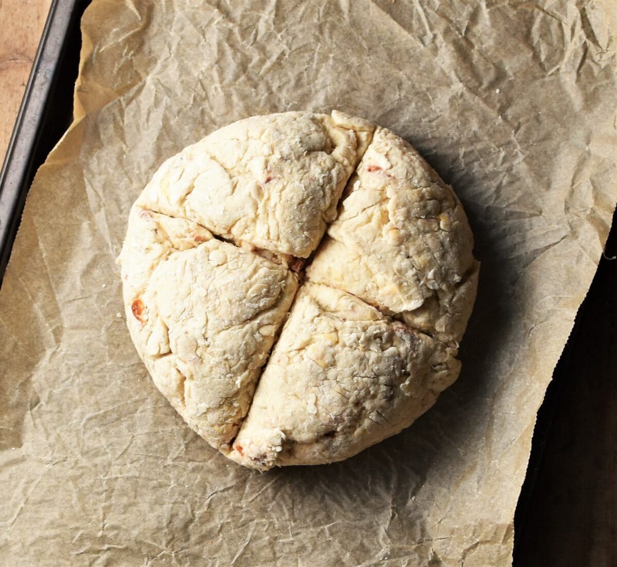 Unbaked sun dried tomato bread on top of parchment.
