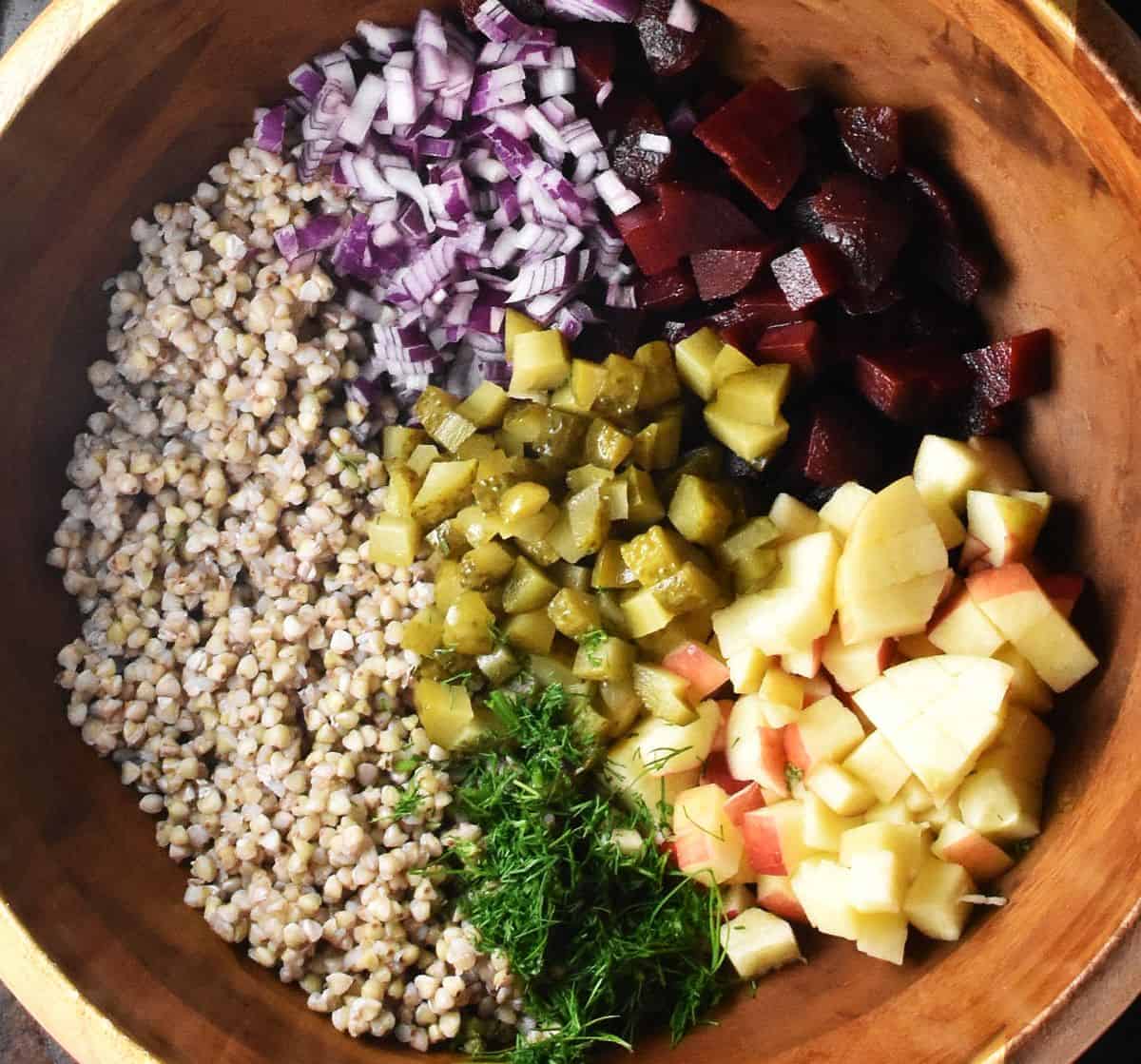 Buckwheat, cubed vegetables and chopped dill in brown bowl.