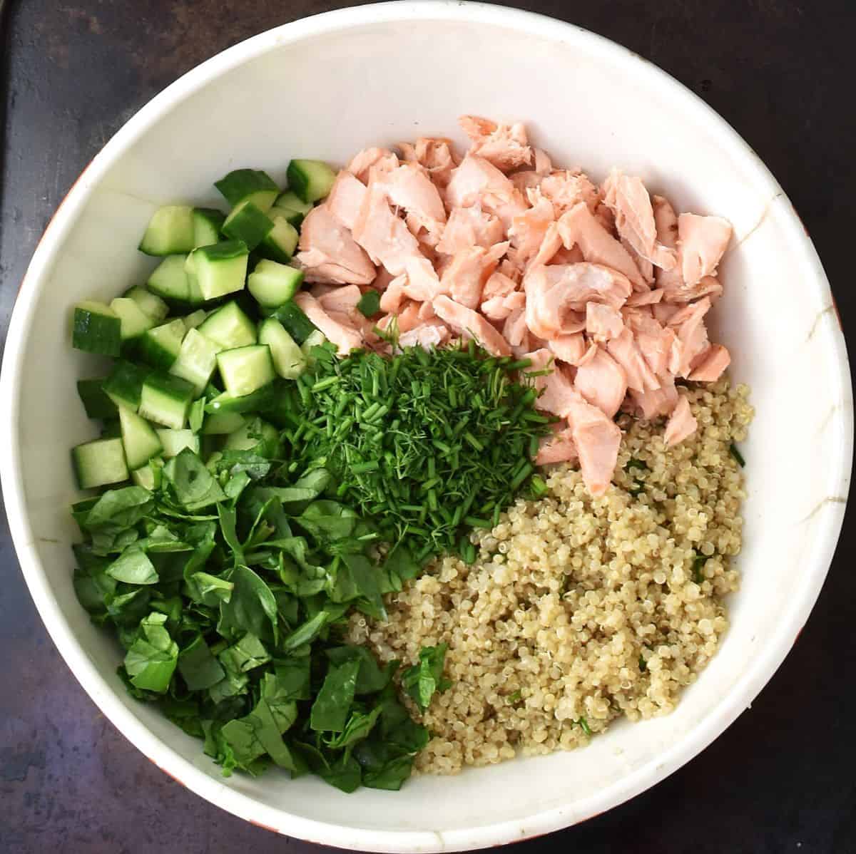 Salmon quinoa salad ingredients assembled in large white bowl.