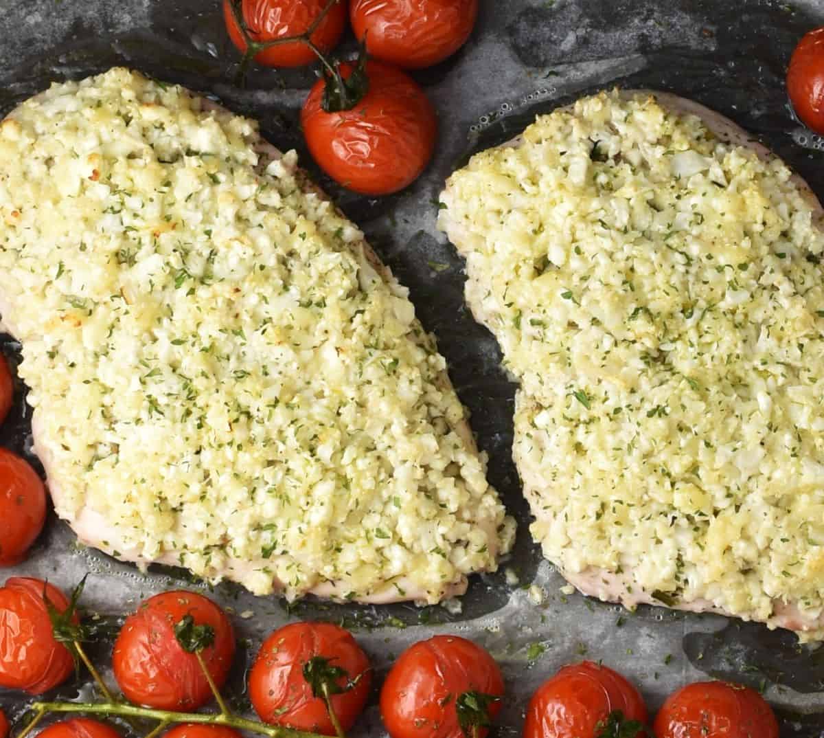 2 chicken breasts with cauliflower crust surrounded by mini tomatoes on vine.