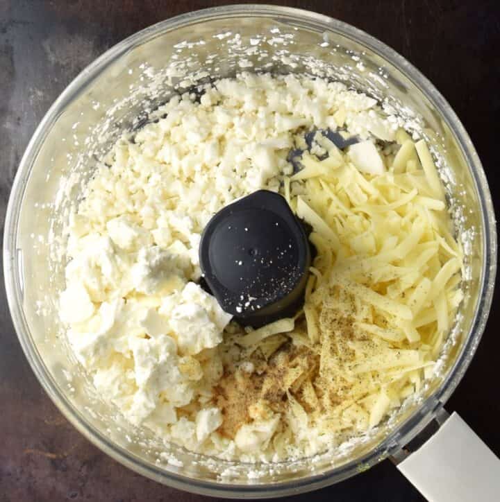 Chopped cauliflower, crumbled feta, grated cheese and spice in blender bowl.