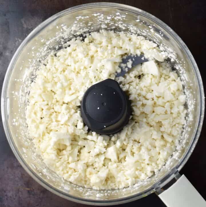 Cauliflower pieces in food processor bowl.