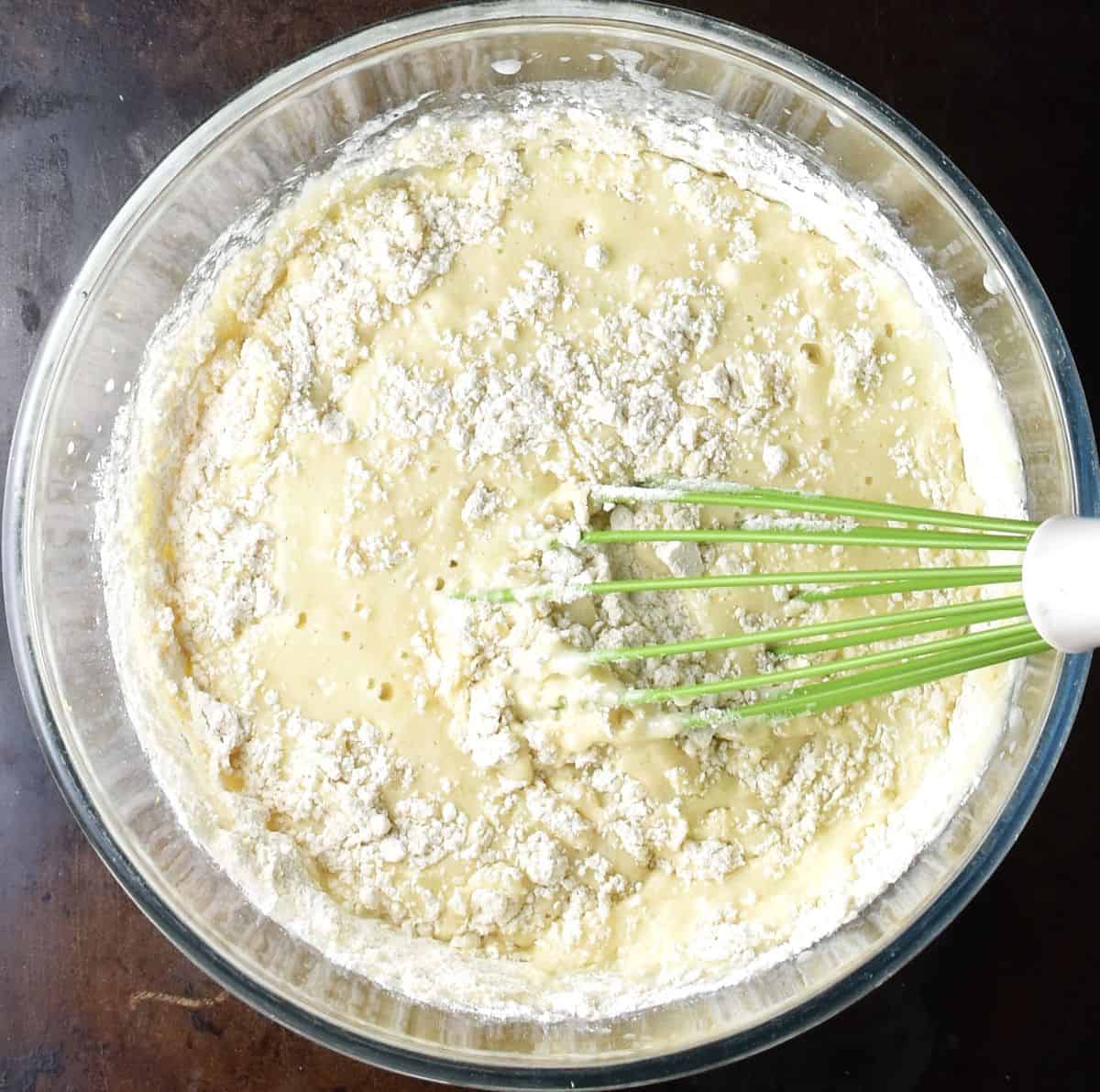 Making lime muffin batter in glass bowl with whisk.