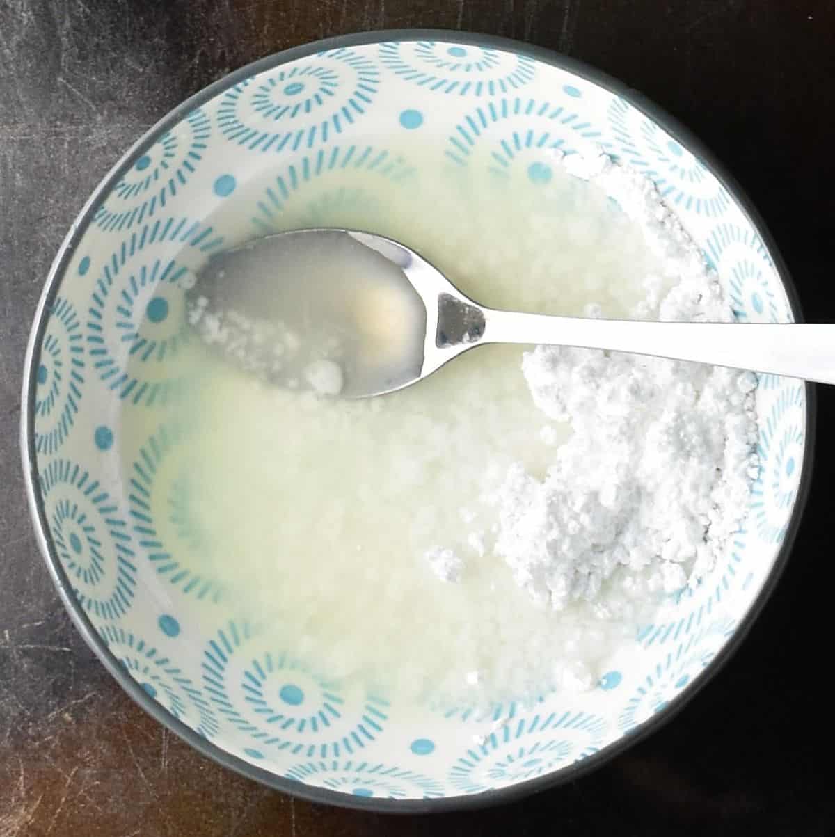 Lime juice and confectioners' sugar in blue bowl with spoon.
