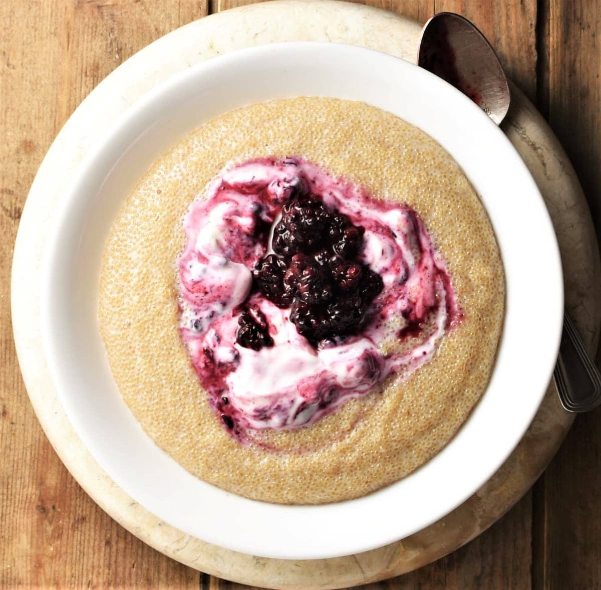 Amaranth porridge with fruit and yogurt in white bowl.