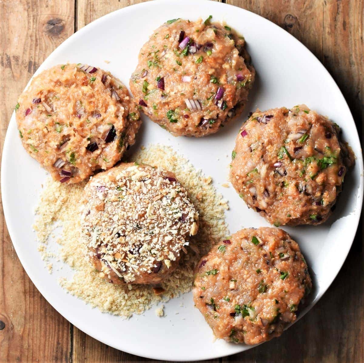 Coating 5 chicken burgers in breadcrumbs.