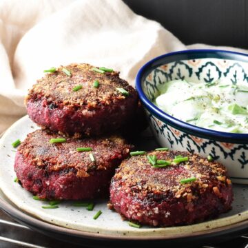 Side view of crispy beet patties on plate with salad.