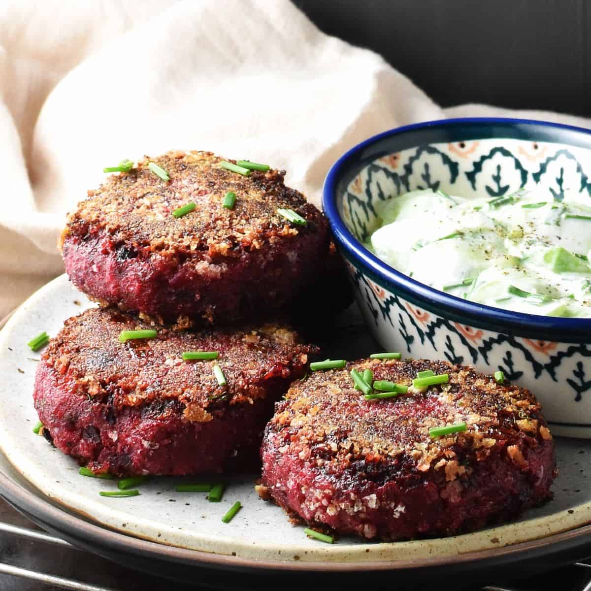 Side view of crispy beet patties on plate with salad.