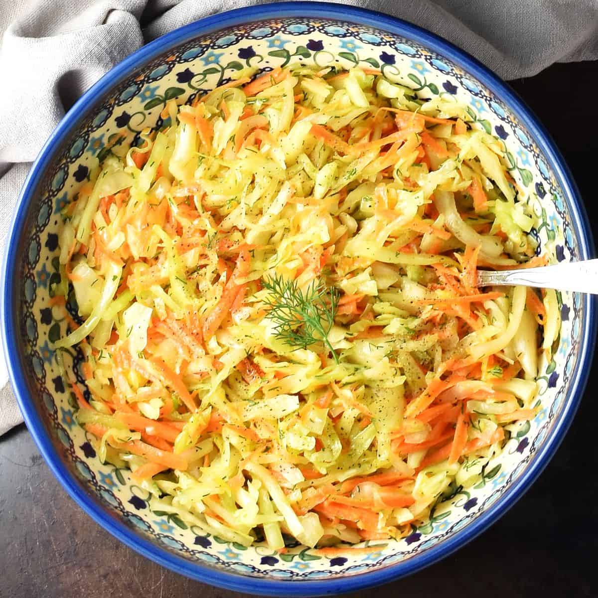 Top down view of Polish coleslaw in traditional Polish ceramic bowl with spoon.