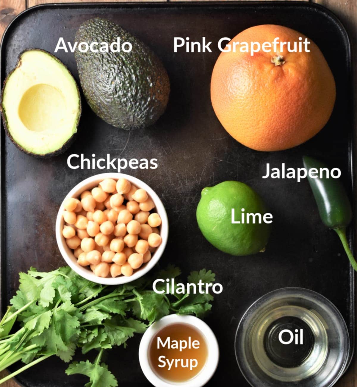 Grapefruit and avocado salad ingredients against black background.