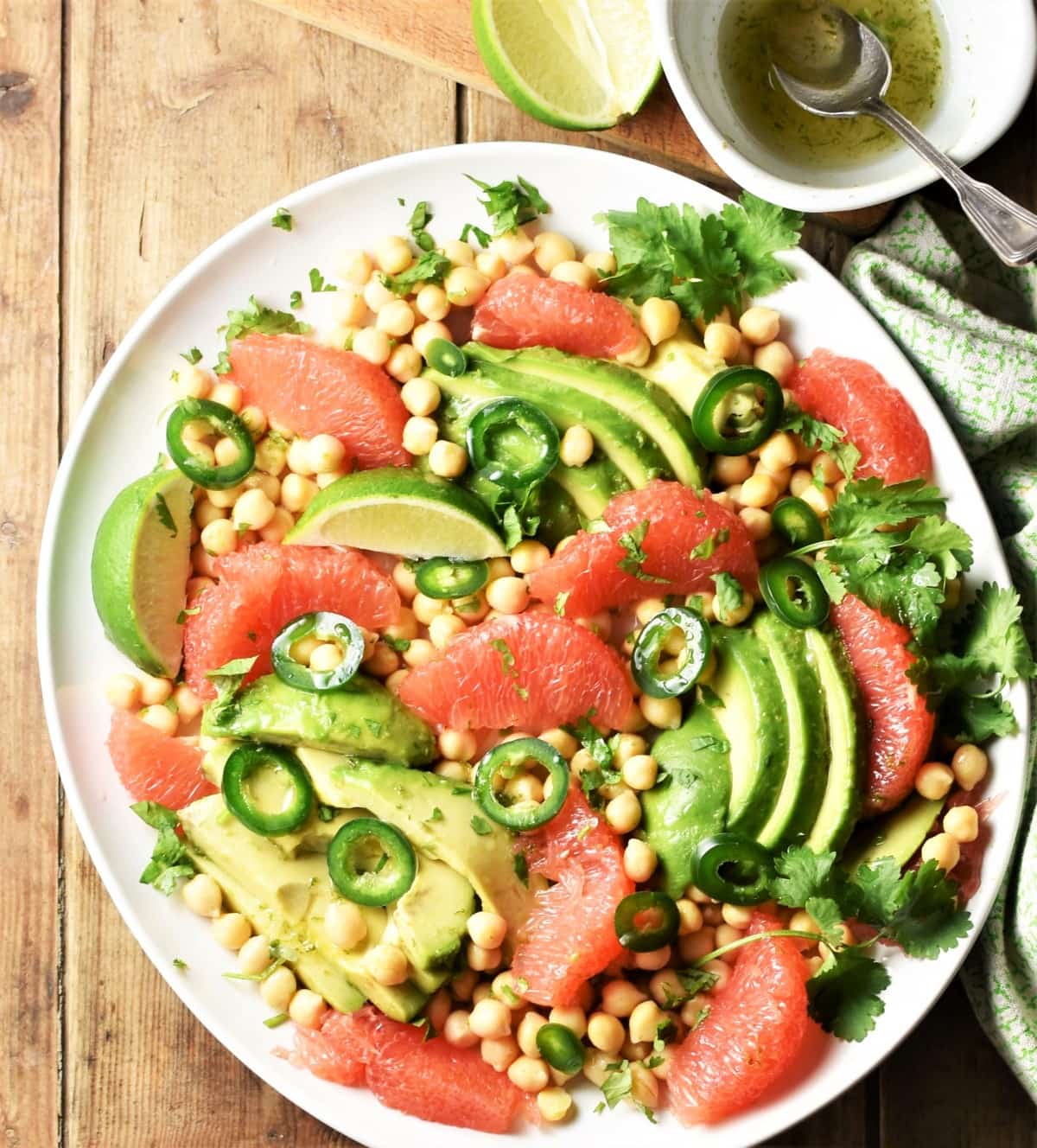 Grapefruit, avocado and chickpea salad on large plate with dressing in top right corner.