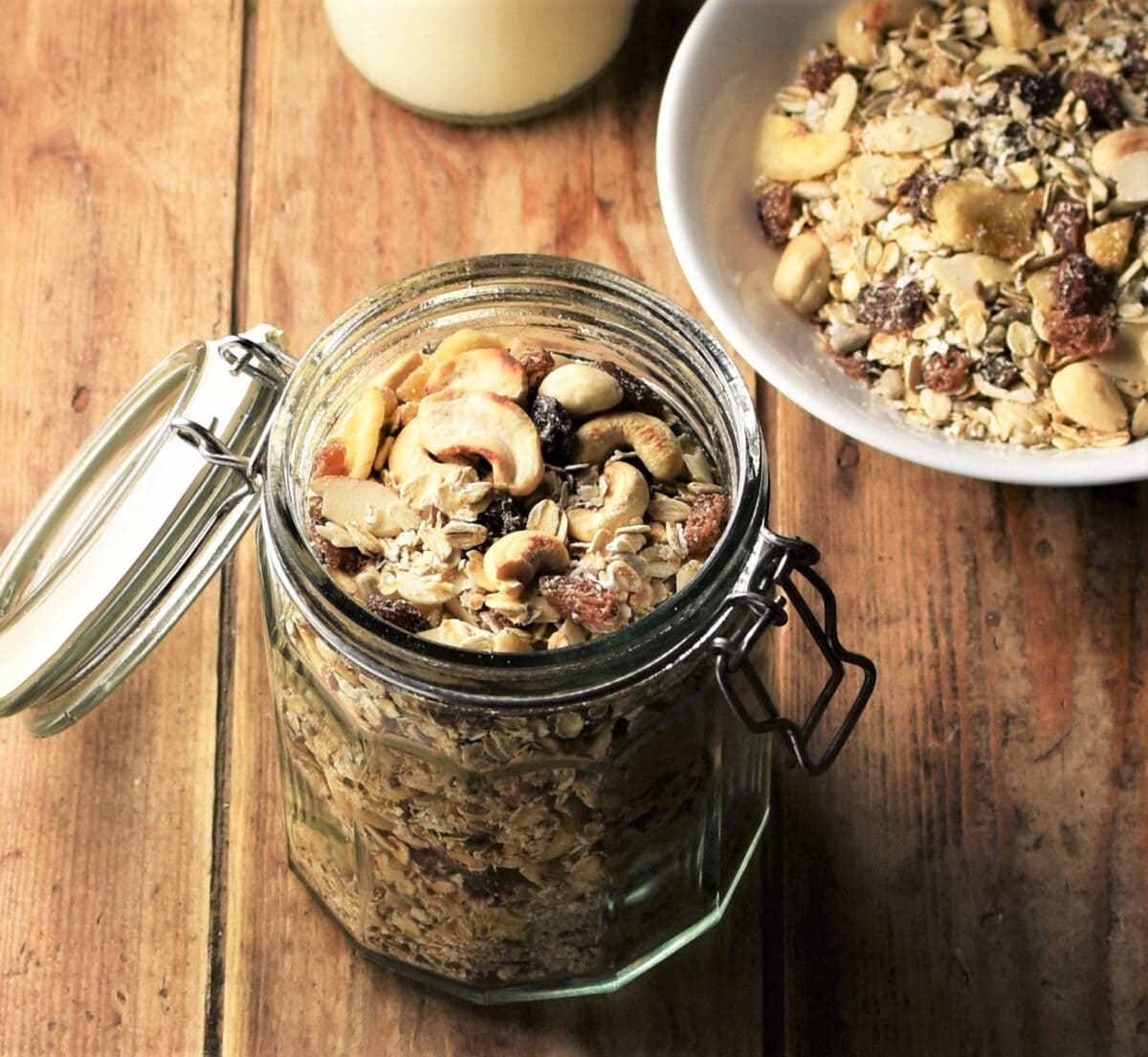 Muesli in open jar with muesli in bowl in top right corner.