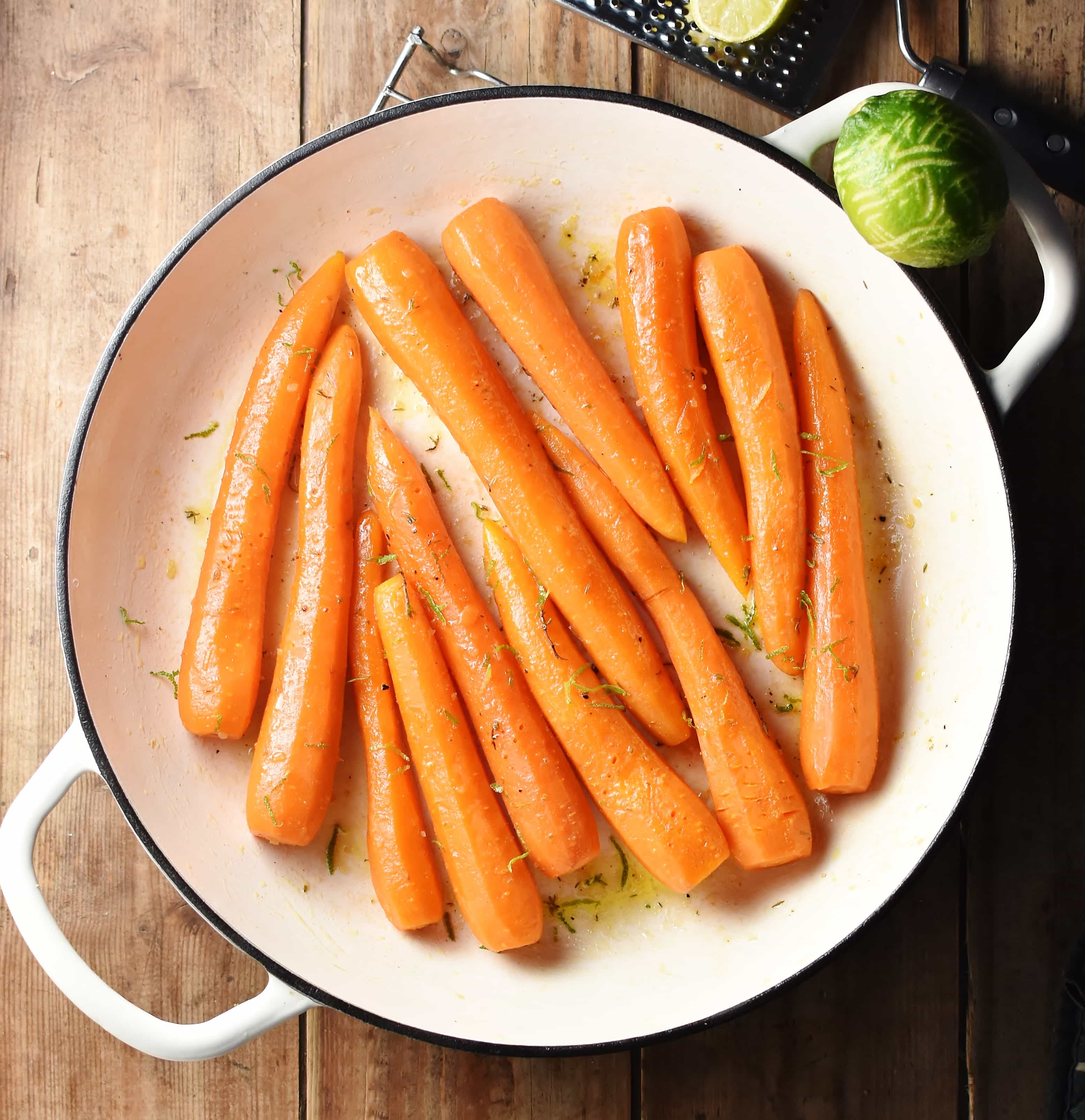 Braised carrots in large white pan, with lime to the right.