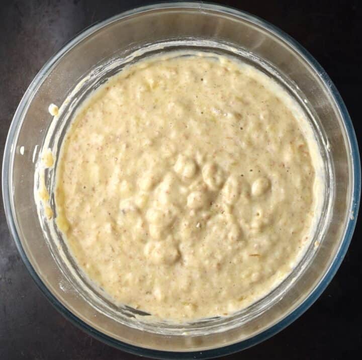 Top down view of banana and yogurt pancake batter in glass bowl.
