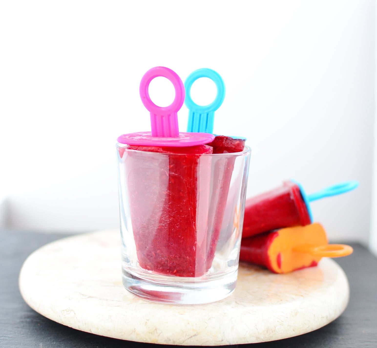 Side view of rooibos tea popsicles in glass and on top of marble plate.