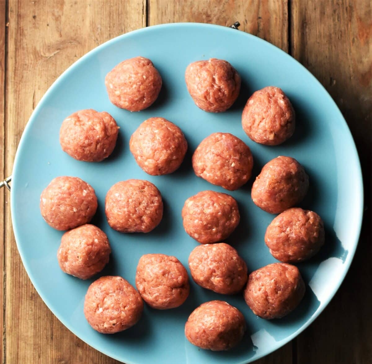 Raw meatballs on blue plate.