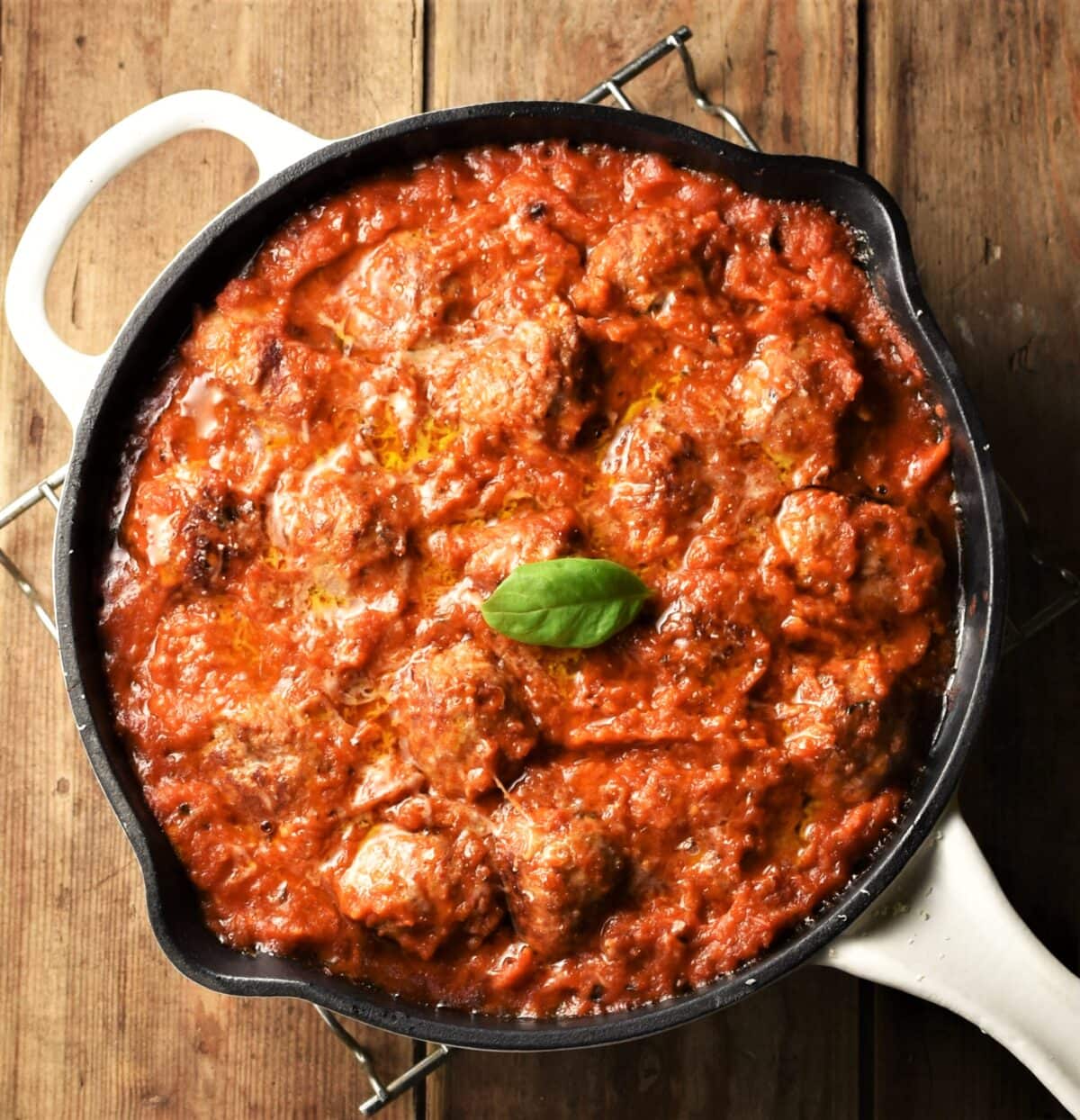 Meatballs in tomato sauce in pan with white handle.