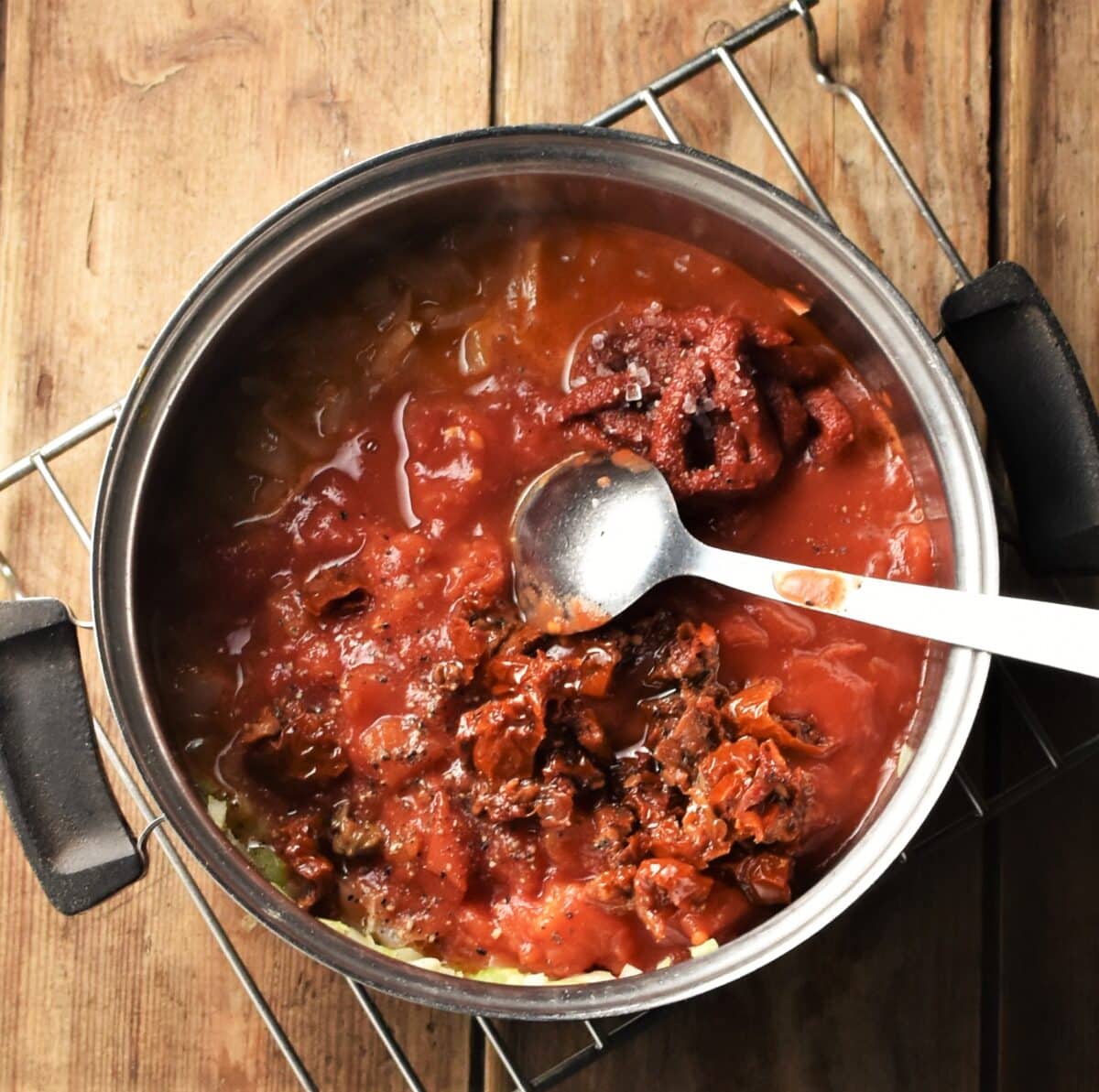 Tomato sauce mixture in pot with spoon.