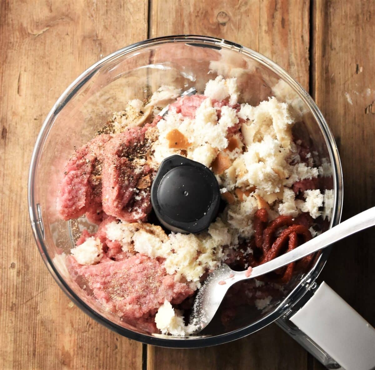 Ground turkey, bread, tomato paste and spoon in blender bowl.