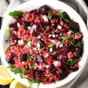 Top down view of beet pasta salad with feta in white bowl.