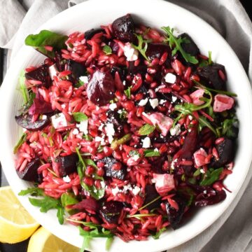Top down view of beet pasta salad with feta in white bowl.