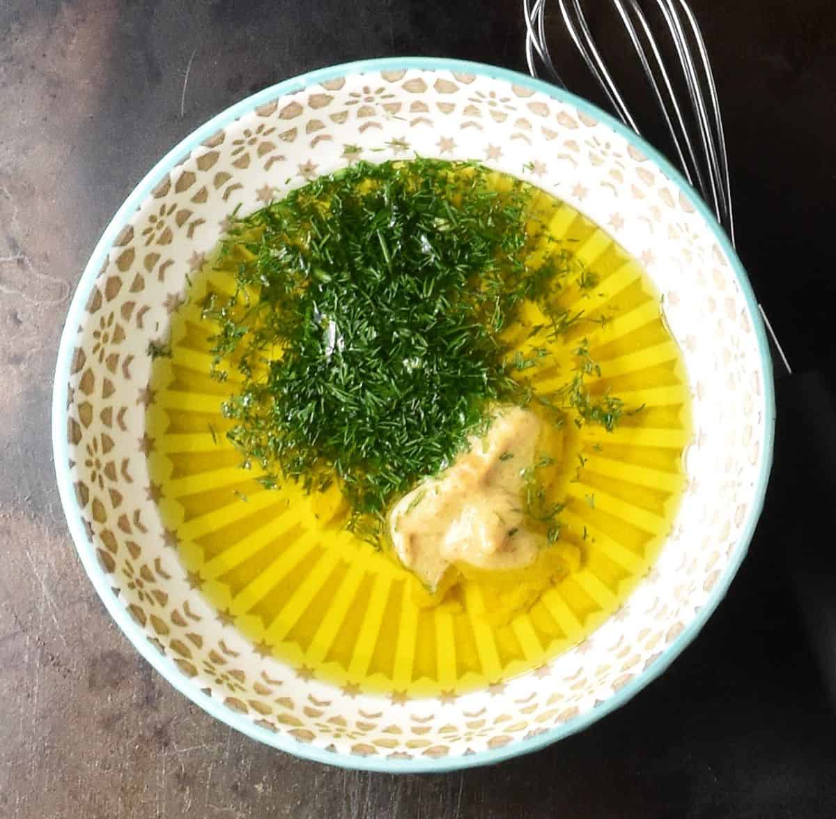 Oil, mustard and chopped dill in small grey bowl.