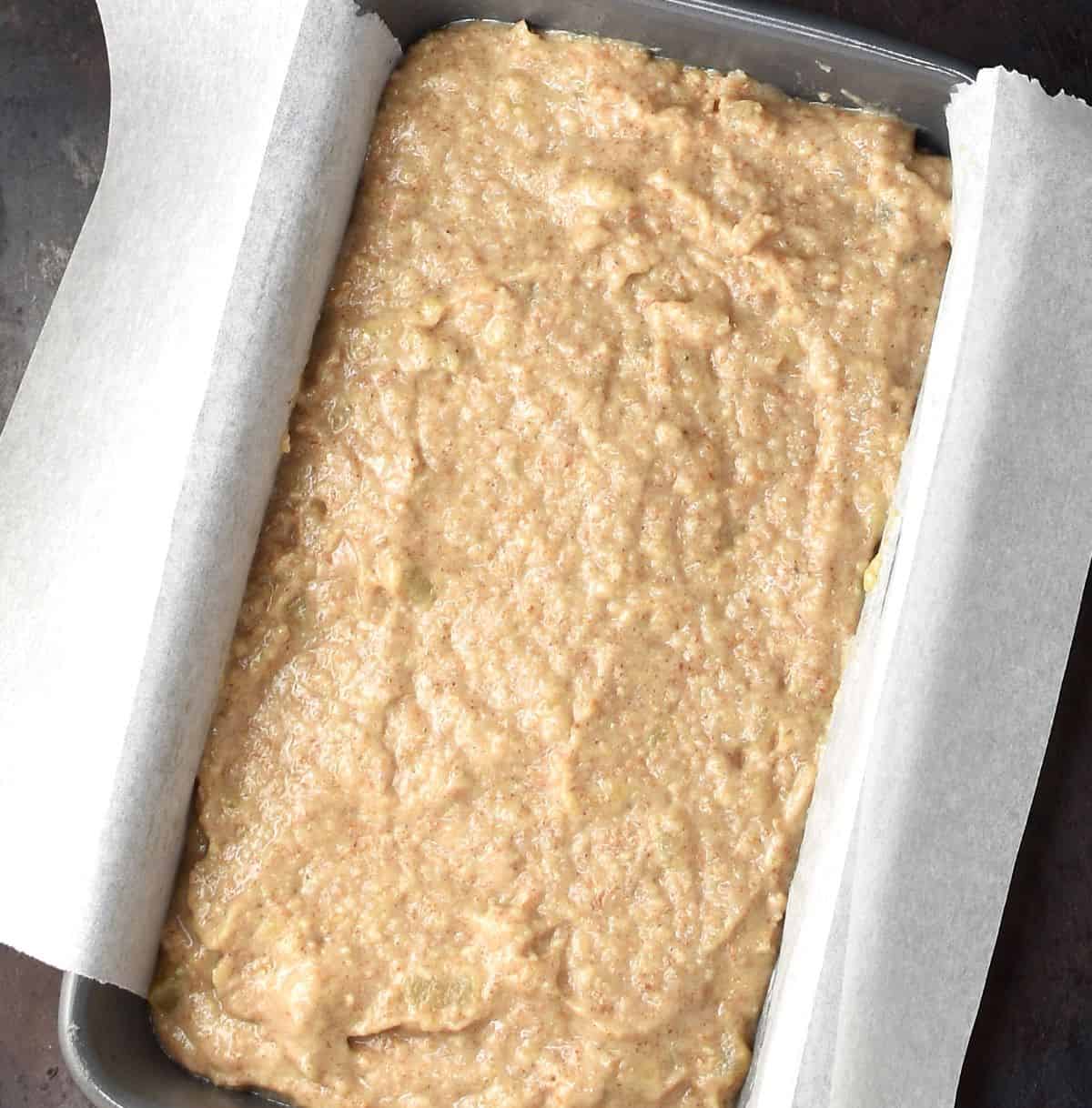 Top down view of banana pear bread batter in loaf pan with parchment.
