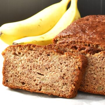Side view of banana pear bread with bananas in background.